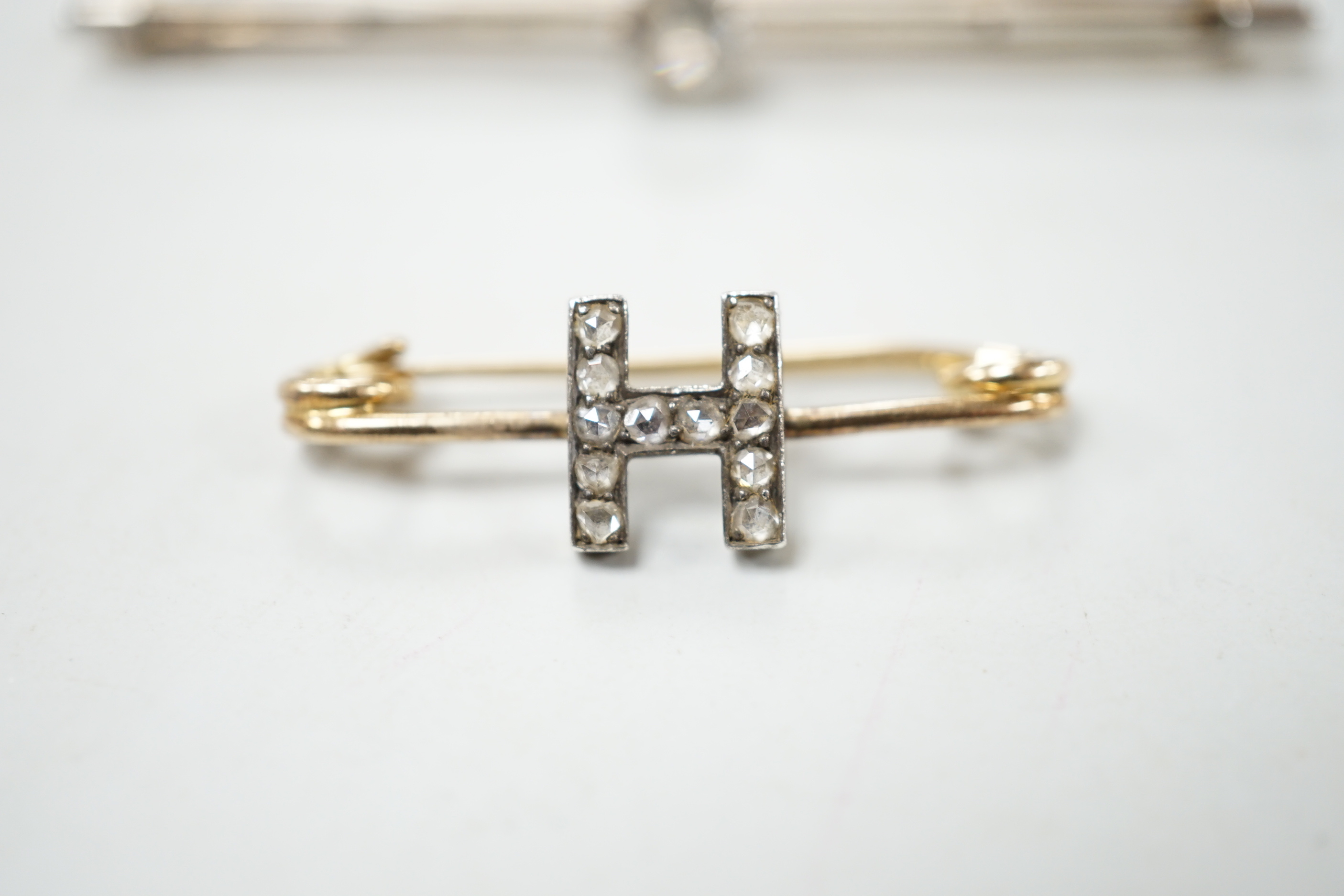An early 20th century yellow metal and rose cut diamond set initial 'H' brooch, 32mm and a yellow metal and aquamarine set bar brooch, gross weight 7.1 grams.